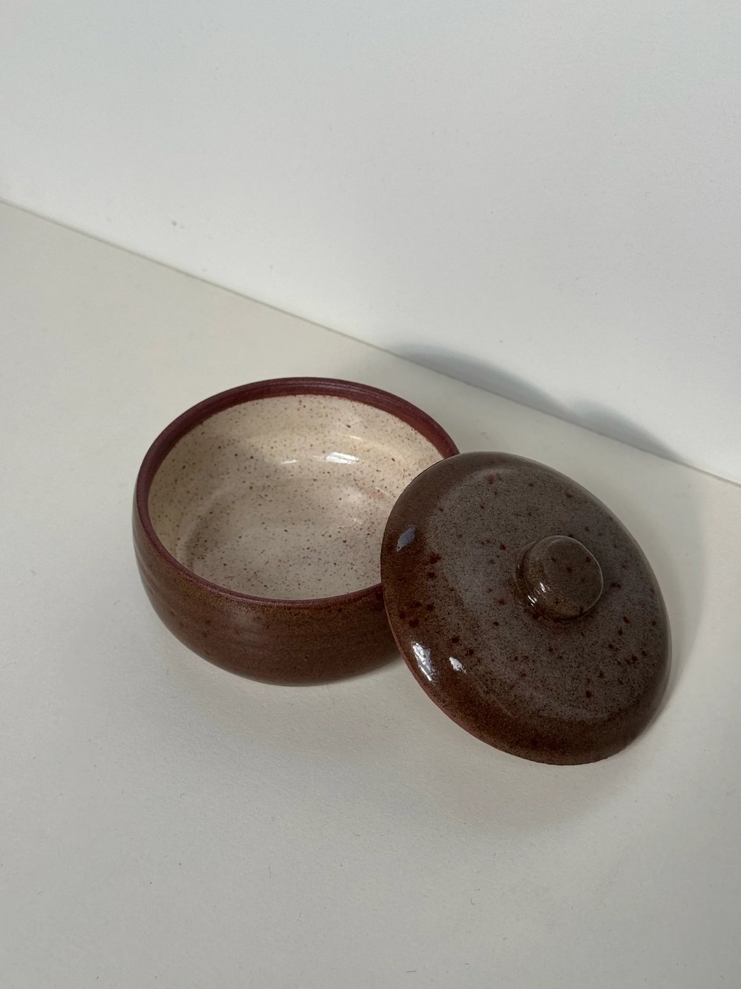 Small lidded jar, speckled brown outside, cream inside, view 1